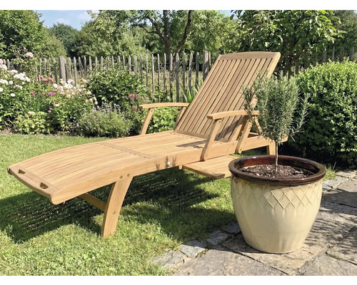 Holzgartenliege neben einem Topf mit Pflanze im Garten