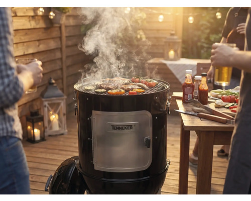 Rauchgrill mit Fleisch und Gemüse auf dem Grillrost bei einer Grillparty im Garten.