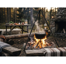 Szene im Freien mit Dreibein, Kochtopf über dem Lagerfeuer und Tisch mit Zutaten