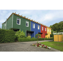 Moderne Reihenhäuser mit bunten Holzfassaden und einer gestalteten Gartenanlage mit Hecken und Blumenbeet.