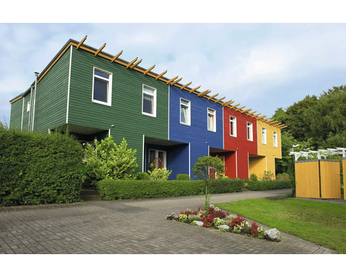 Moderne Reihenhäuser mit bunten Holzfassaden und einer gestalteten Gartenanlage mit Hecken und Blumenbeet.