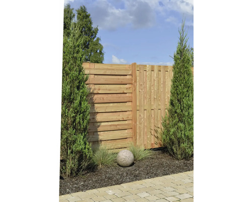Sichtschutzzaun aus Holz mit horizontalen und vertikalen Lamellen, eingerahmt von Zypressen in einem Garten.