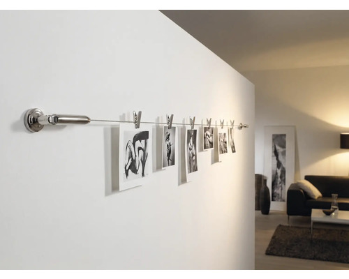 Fotos an einer Wandschiene mit Klammern im Wohnzimmer