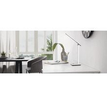 Tischleuchte auf einem Schreibtisch in einem hellen Raum.