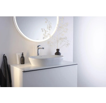 Helles Badezimmer mit weißem Aufsatzwaschbecken, verchromter Armatur, hellem Waschtischunterschrank und rundem LED-Spiegel.