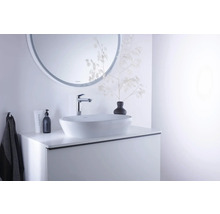 Modernes Badezimmer mit weißem Aufsatzwaschbecken auf einem weißen Waschtischunterschrank, verchromter Armatur und rundem Wandspiegel.