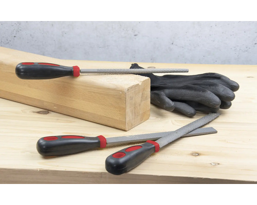 Holzblock, Handschuhe und verschiedene Feilen auf einer Holzoberfläche.