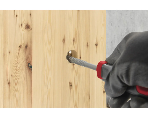 Ein Holzbrett wird mit einer Raspel bearbeitet.