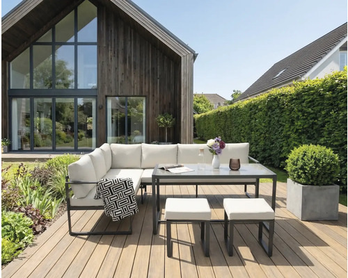 Gartenlounge-Set mit Tisch und Hockern auf einer Holzterrasse vor einem Haus