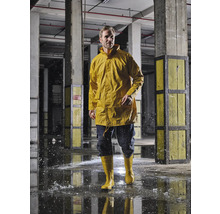 Mann in gelber Regenjacke und Gummistiefeln in einer Industriehalle