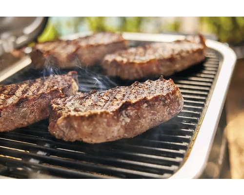 Auf einem Grill liegen Steaks.