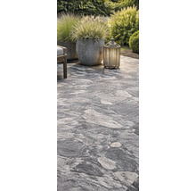 Verlegter Terrassenboden mit Pflanzgefäßen und Windlicht im Garten