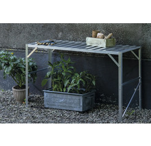 Pflanztisch aus Aluminium mit Lamellenoberfläche im Garten, darunter ein Pflanzkübel und daneben ein Blumentopf.