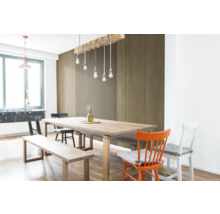 Heller Essbereich mit Holztisch und Wandpaneelen in Holzoptik, bestehend aus Lamellen und glatten Holzdekor-Elementen.