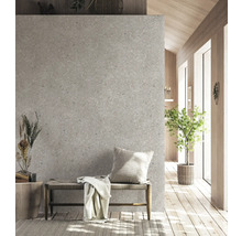 Moderne Innenraumszene mit Wand in grauer Terrazzo-Optik, Holzbank mit Geflechtsitz, Zierkissen und Decke auf hellem Holzboden.