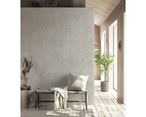 Moderne Innenraumszene mit Wand in grauer Terrazzo-Optik, Holzbank mit Geflechtsitz, Zierkissen und Decke auf hellem Holzboden.