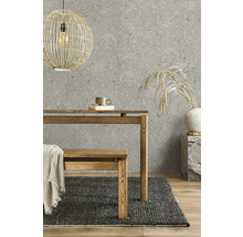 Vliestapete mit Steinoptik in Grau, kombiniert mit einem Holztisch, einer Holzbank, einem dunklen Webteppich und einer Korb-Hängeleuchte.