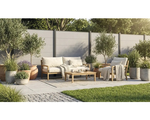 Modernes Garten-Lounge-Set aus Holz auf einer hellen Fliesenterrasse mit Sichtschutzzaun, Olivenbäumen und Gräsern in Töpfen.