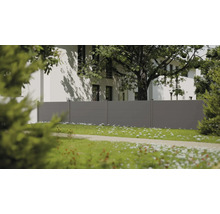 Moderner grauer Sichtschutzzaun mit horizontalen Paneelen in einem hellen Garten mit weißem Haus und großem Baum im Hintergrund.