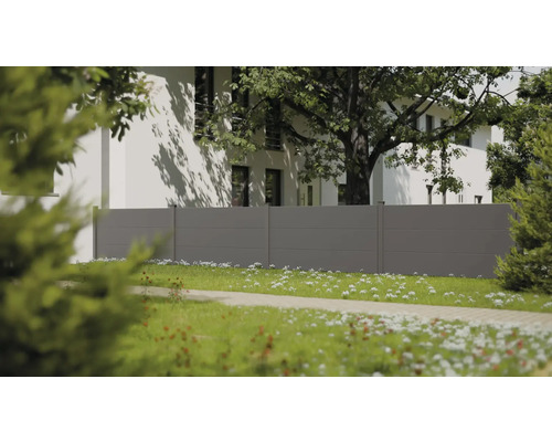 Moderner grauer Sichtschutzzaun mit horizontalen Paneelen in einem hellen Garten mit weißem Haus und großem Baum im Hintergrund.