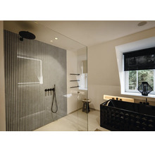 Modernes Badezimmer mit begehbarer Glasdusche, Wandpaneelen in Lamellenoptik, schwarzen Armaturen und einer strukturierten schwarzen Badewanne.