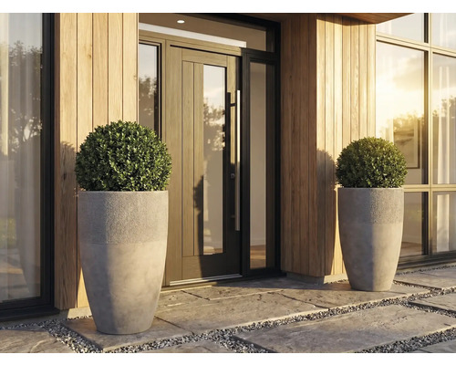 Moderner Eingangsbereich mit zwei hohen grauen Pflanzgefäßen aus Betonoptik, bestückt mit runden Buchsbaumkugeln vor einer Holzfassade.