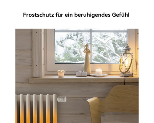 Ein Heizkörper mit einem smarten Heizkörperthermostat vor einem Fenster mit verschneiter Aussicht und winterlicher Dekoration.