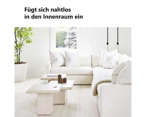 Helles, modernes Wohnzimmer mit einem weißen Ecksofa, hölzernen Couchtischen, einer großen Zimmerpflanze und einem kleinen runden Sensor auf dem Tisch.