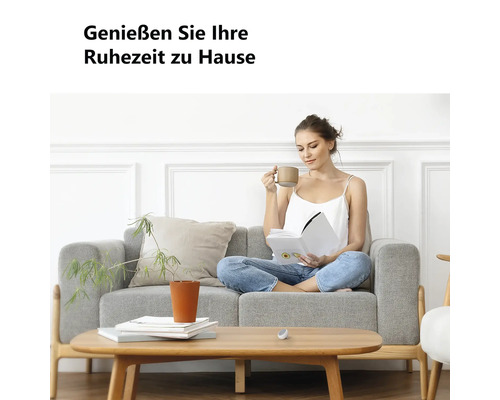 "Eine Frau liest auf einem grauen Stoffsofa in einem hellen Wohnzimmer