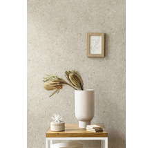 Vliestapete in Steinoptik mit Terrazzo-Muster in einem Wohnraum kombiniert mit einer weißen Vase, Trockenblumen und einem Holzrahmen.