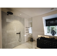 Modernes, helles Badezimmer mit begehbarer Dusche, schwarzen Armaturen, grauer Wand in Steinoptik und einer schwarzen Badewanne mit Struktur.