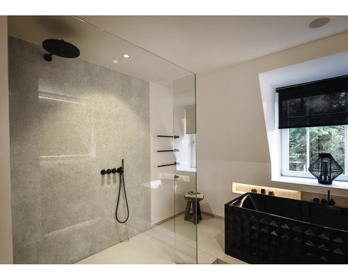 Modernes, helles Badezimmer mit begehbarer Dusche, schwarzen Armaturen, grauer Wand in Steinoptik und einer schwarzen Badewanne mit Struktur.