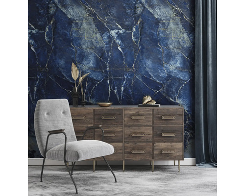 Fototapete mit blauem Marmormuster in einem Wohnzimmer mit Holzkommode und grauem Sessel.