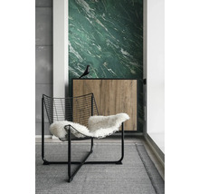 Modernes Zimmer mit grüner Marmortapete, schwarzem Drahtsessel mit weißem Fell und Sideboard in Holzoptik auf grauem Teppich.