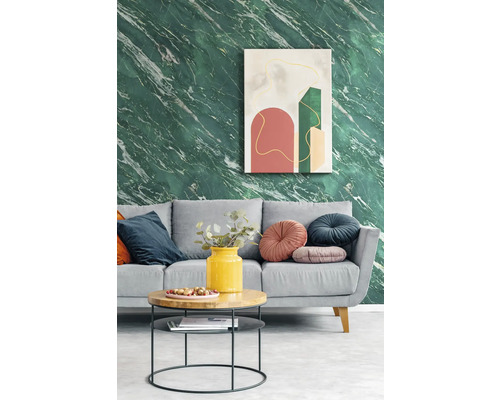 Modernes Wohnzimmer mit Tapete in grüner Marmoroptik, grauem Sofa mit dekorativen Kissen und einem runden Couchtisch vor abstrakter Wandkunst.