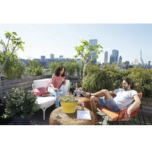 Helle Dachterrasse mit Stadtblick, Gartenmöbeln, Topfpflanzen und zwei Personen auf einem Holzdeck.
