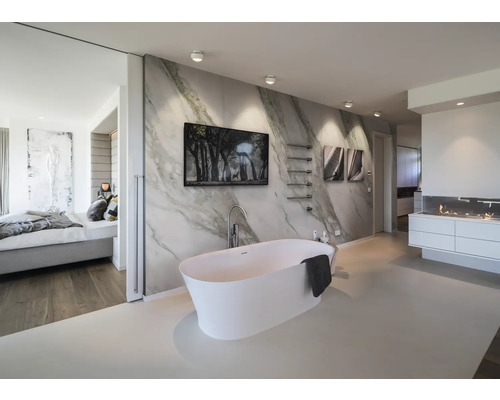 Modernes Badezimmer mit freistehender weißer Badewanne vor Marmorwand, Wandbildern, Handtuchhalter und heller Beleuchtung.