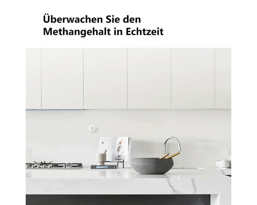 Helle, moderne Küche mit weißen Schränken und Marmorarbeitsplatte. An der Wand ist ein runder Methansensor zur Echtzeit-Überwachung montiert.