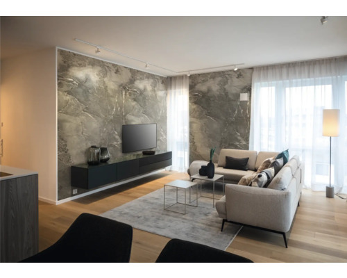 Modernes Wohnzimmer mit Marmoreffekt-Wand, schwarzem Hängeboard, hellem Ecksofa, Holzboden und hellen Fenstern mit transparenten Vorhängen.