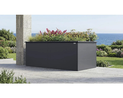 Großes, anthrazitfarbenes Weka Metall-Hochbeet auf einer Terrasse mit Meerblick, bepflanzt mit Gräsern und verschiedenen Pflanzen.