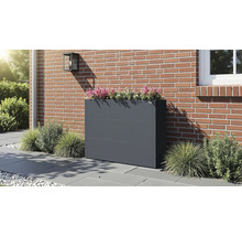 Anthrazitfarbener Pflanzkübel aus Metall auf einer Terrasse vor einer Backsteinwand, bepflanzt mit Zierpflanzen.