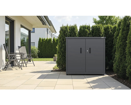 Anthrazitfarbener Metall-Geräteschrank mit Doppeltüren auf einer Terrasse neben einer Hecke und Gartenstühlen.