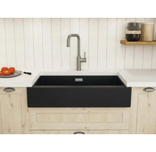Schwarze Schürzen-Spüle in einer hellen Holzküche mit einer hohen gebürsteten Armatur und weißer Arbeitsplatte.