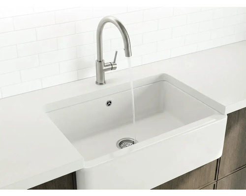 Landhausspüle Blanco VILLAE Farmhouse 79,5 x 46 cm weiß 525163 Weißes Spülbecken im Landhausstil mit hohem Wasserhahn aus Metall und fließendem Wasser in einer hellen, organisierten Küche.