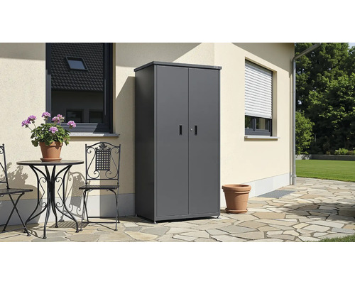 Anthrazitgrauer Metall-Geräteschrank mit zwei Türen und Flachdach auf einer Steinterrasse an einer Hauswand neben Gartenmöbeln.