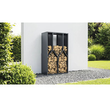 Anthrazitfarbenes Kaminholzregal aus Metall, gefüllt mit Brennholz, in einem Garten auf Kies vor einer Wand.