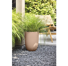 Hoher runder Pflanzkübel mit vertikaler Wellenstruktur und Ziergras auf einer Kiesfläche im Garten neben einem Holzpfosten und einem Gartenstuhl.