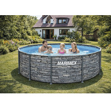 Eine Familie nutzt einen runden Marimex Aufstellpool mit Steinoptik in einem sonnigen Garten vor einem Wohnhaus.