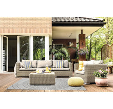 Helle Terrasse mit grauer Rattan-Sitzgruppe, Outdoorteppich mit Kreismuster, gelbem Strick-Pouf und Topfpflanze auf Holzdielen.