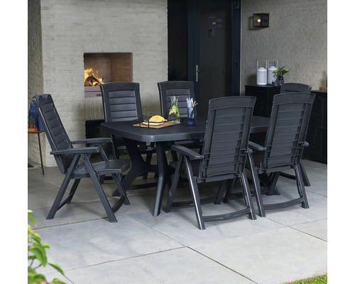 Gartenset aus dunklem Kunststoff mit rechteckigem Tisch und Hochlehner-Stühlen auf einer Terrasse mit Außenkamin und Fliesenboden.